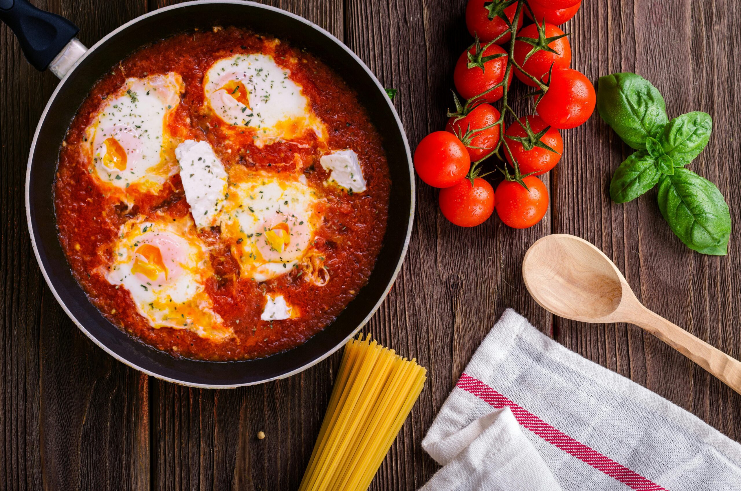 der joghurt-effekt: gesund abnehmen mit leckeren variationen 4 schwarze pfanne mit spaghettisauce in der nähe von brauner holzkelle und reifen tomaten mit joghurt